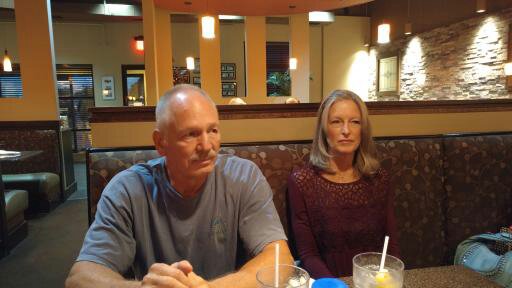 Bob and Jamie Woodford sitting in booth at restaurant. Goodness, they don't look happy.